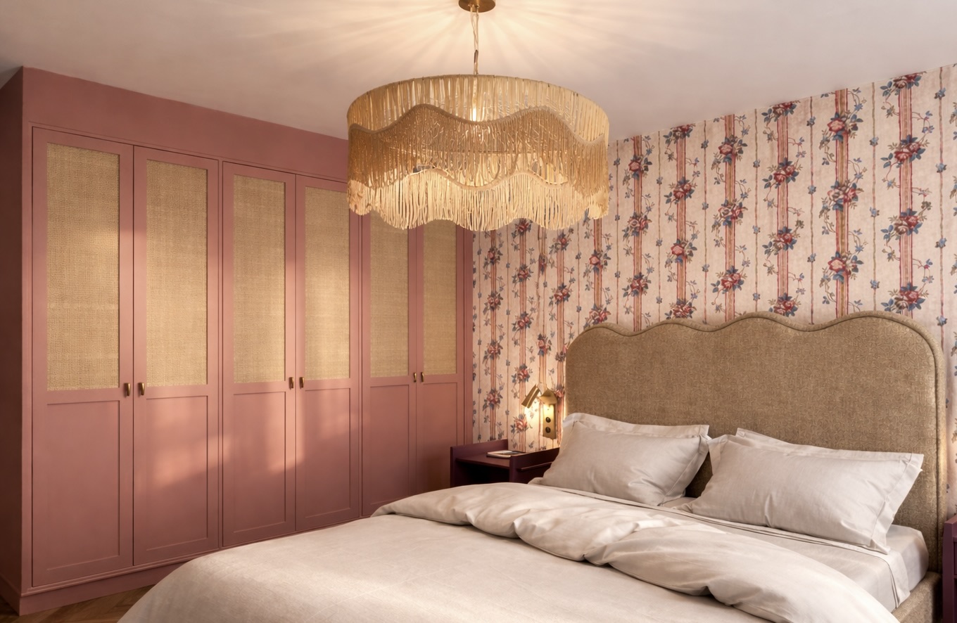 Chambre : armoire cannée rose poudré, papier peint fleuri, tête de lit ondulée en tissu, suspension à franges et literie blanche