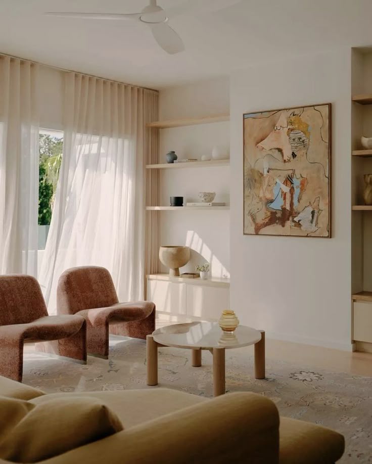 Séjour chaleureux de la maison La Youte : cheminée blanche, fauteuils en rotin, canapé crème et porte-fenêtre ouvrant sur la végétation