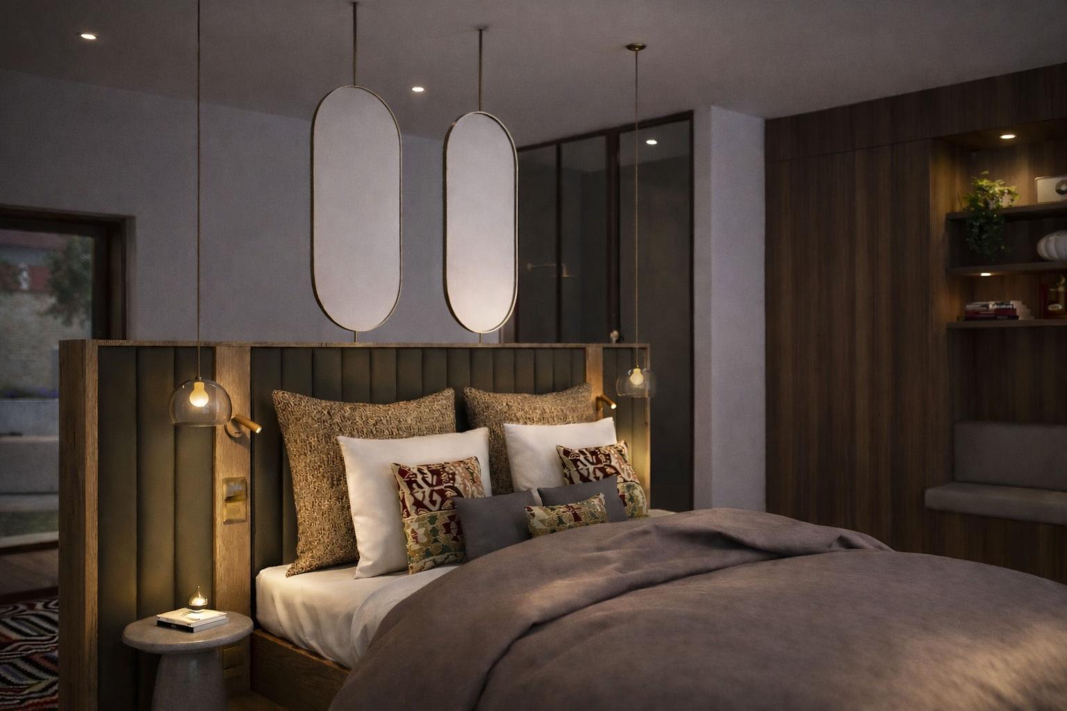 Chambre feutrée aux teintes sombres : tête de lit capitonnée à cannelures, deux miroirs ovales en laiton, suspensions et coussins à motifs, panneaux de bois